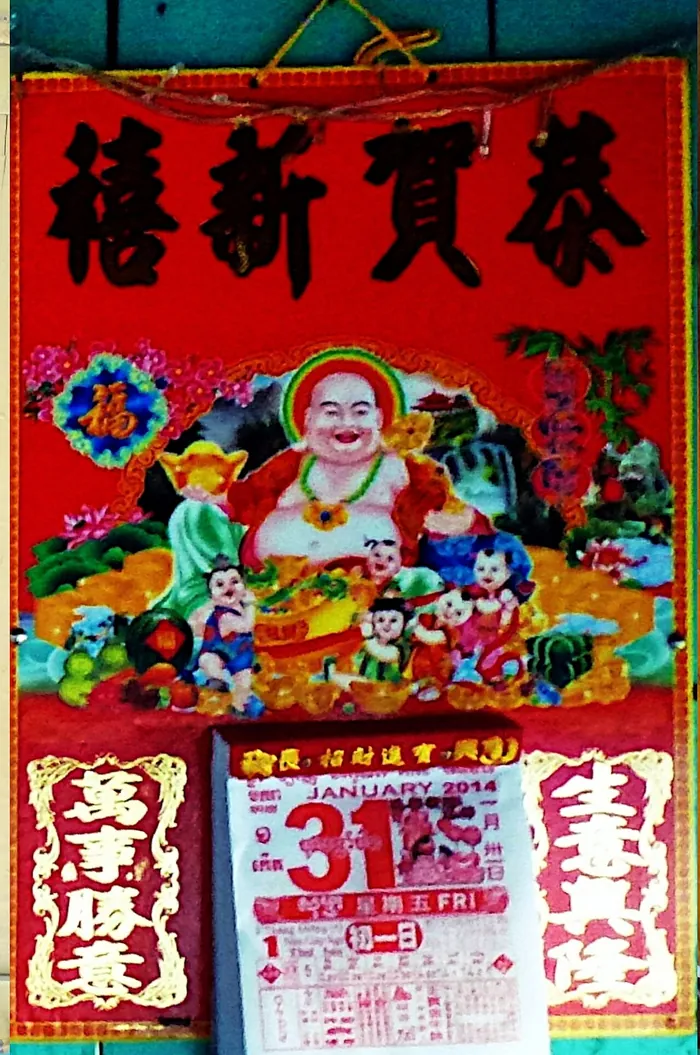 A red Chinese New Year poster with a smiling Buddha figure above a day calendar showing 31 January 2014